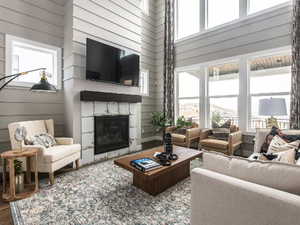 Living room featuring wood walls, a fireplace, hardwood / wood-style floors, and a high ceiling. *Photos are of our Stella model home.  Actual colors and finishes will vary.  See agent for additional information.