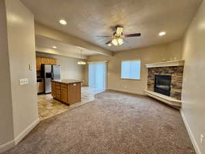 Kitchen with decorative light fixtures, a center island, light carpet, a textured ceiling, and stainless steel appliances