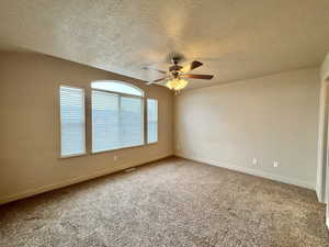 Spare room with ceiling fan, carpet floors, and a textured ceiling