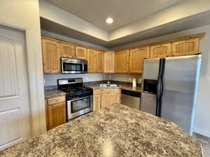 Kitchen featuring a raised ceiling, appliances with stainless steel finishes, and sink