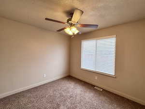 Spare room with ceiling fan, carpet, and a textured ceiling