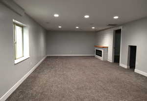 Unfurnished living room with a large fireplace and dark carpet