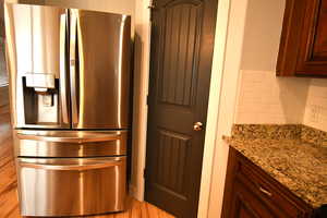 Kitchen featuring light stone countertops, stainless steel fridge with ice dispenser, and decorative backsplash