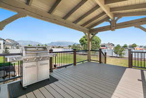 Wooden deck with a mountain view, area for grilling, and a lawn