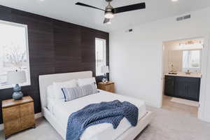 Carpeted bedroom featuring ceiling fan, connected bathroom, and sink