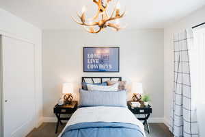 Bedroom with dark carpet and a chandelier