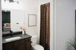 Bathroom with vanity, curtained shower, and toilet