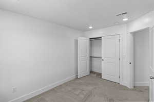 Bedroom 2 with light colored carpet and a closet