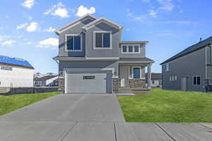 View of front of house featuring stone siding, stucco siding, a front yard, and driveway
