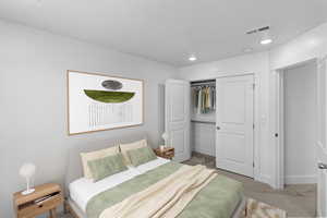 Bedroom 2 with light colored carpet and a closet