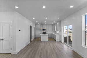 Kitchen with pendant lighting, sink, a center island, stainless steel appliances, and light wood-type flooring