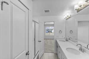 Bathroom with tile patterned floors, a shower with door, vanity, and a linen closet