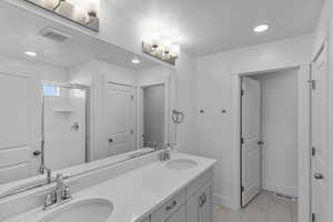 Bathroom featuring tile patterned flooring, vanity, and a shower with shower door