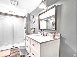 Bathroom with vanity, hardwood / wood-style floors, and a shower with shower door