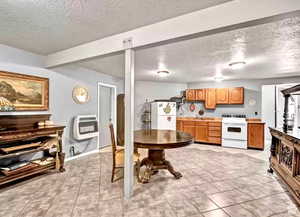 Kitchen featuring heating unit, white appliances, and a textured ceiling