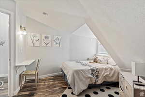 Bedroom featuring lofted ceiling, dark wood-type flooring, and a textured ceiling