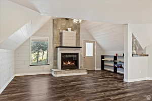 Bonus room with lofted ceiling, dark wood-type flooring, and a large fireplace