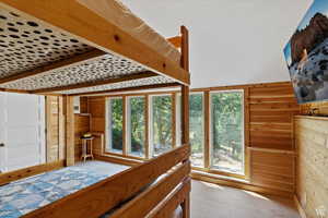 Bedroom with light wood-type flooring and wooden walls