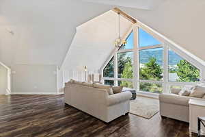 Living room with lofted ceiling, dark hardwood / wood-style floors, a chandelier, and a mountain view