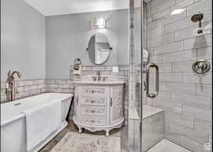 Bathroom with vanity, independent shower and bath, and tile walls