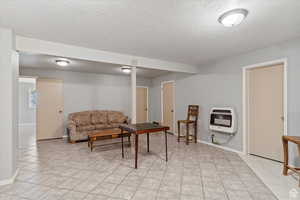 Tiled living room featuring heating unit and a textured ceiling