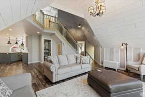 Living room with an inviting chandelier, sink, high vaulted ceiling, and dark hardwood / wood-style floors