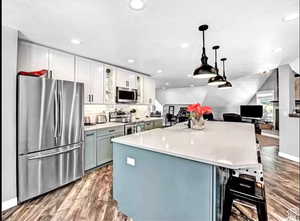 Kitchen featuring hanging light fixtures, appliances with stainless steel finishes, dark hardwood / wood-style floors, and white cabinets