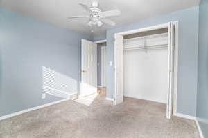 Unfurnished bedroom with light carpet, a textured ceiling, ceiling fan, and a closet