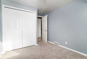 Unfurnished bedroom featuring light colored carpet, a closet, and a textured ceiling