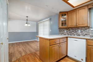 Kitchen featuring kitchen peninsula, dishwasher, light hardwood / wood-style floors, and hanging light fixtures