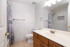 Bathroom featuring vanity, tile walls, tile patterned floors, and toilet