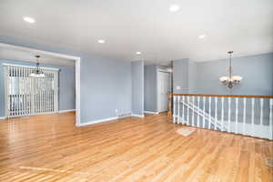 Spare room with a chandelier and light wood-type flooring