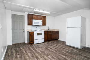 Kitchen featuring dark wood-type flooring, white appliances, and sink