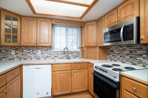 Kitchen featuring dishwasher, range with electric cooktop, sink, and decorative backsplash