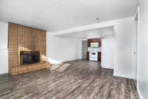 Unfurnished living room with a brick fireplace, dark wood-type flooring, and a drop ceiling