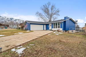 View of front facade with driveway, a front lawn, fence, a mountain view, and an attached garage