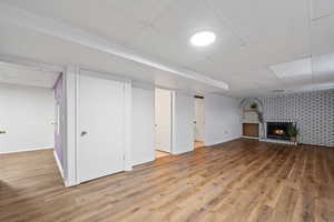 Basement with hardwood / wood-style flooring and brick fireplace.