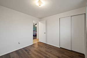 Unfurnished bedroom featuring dark hardwood / wood-style floors, a textured ceiling, and a closet