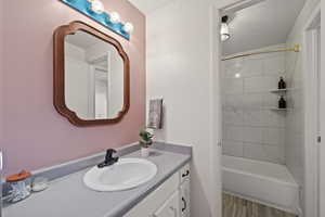 Newly remodeled bathroom - featuring vanity, tiled shower / bath combo, and wood-type flooring.