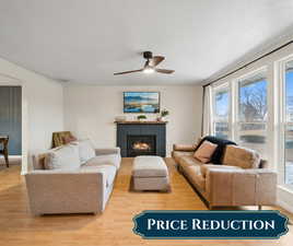 Living room featuring a textured ceiling, a fireplace, wood finished floors, and baseboards