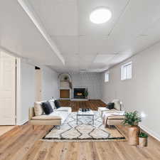 Virtual Staging- Basement family room with wood-type flooring, and a fireplace.