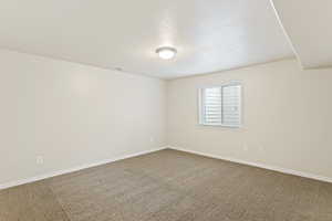 Carpeted spare room with a textured ceiling