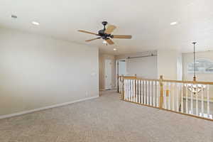 Carpeted empty room with ceiling fan with notable chandelier