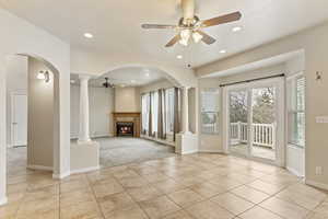 Unfurnished living room featuring decorative columns, a wealth of natural light, light tile patterned floors, and ceiling fan