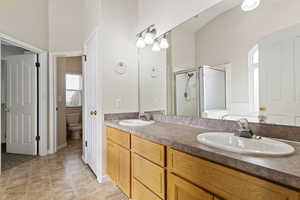 Bathroom with vanity, a shower with shower door, tile patterned floors, and toilet