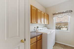 Washroom featuring separate washer and dryer, light tile patterned floors, and cabinets