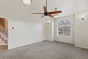 Unfurnished living room featuring ceiling fan, high vaulted ceiling, and carpet