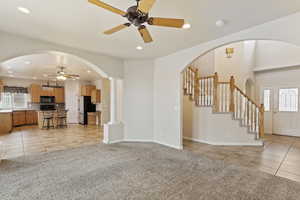 Unfurnished living room featuring sink, light colored carpet, ceiling fan, and ornate columns