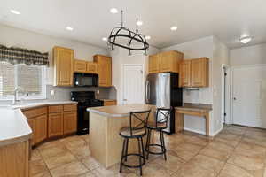 Kitchen featuring light tile patterned flooring, sink, a center island, decorative backsplash, and black appliances