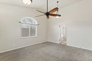 Carpeted spare room featuring high vaulted ceiling and ceiling fan